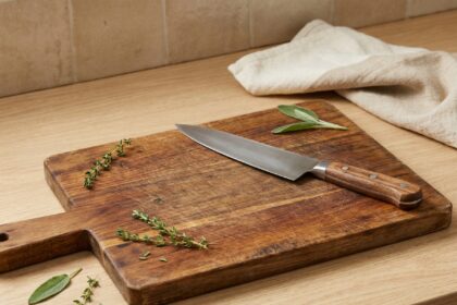 Planche à découper en bois avec grain naturel et couteau de chef sur plan de travail en cuisine